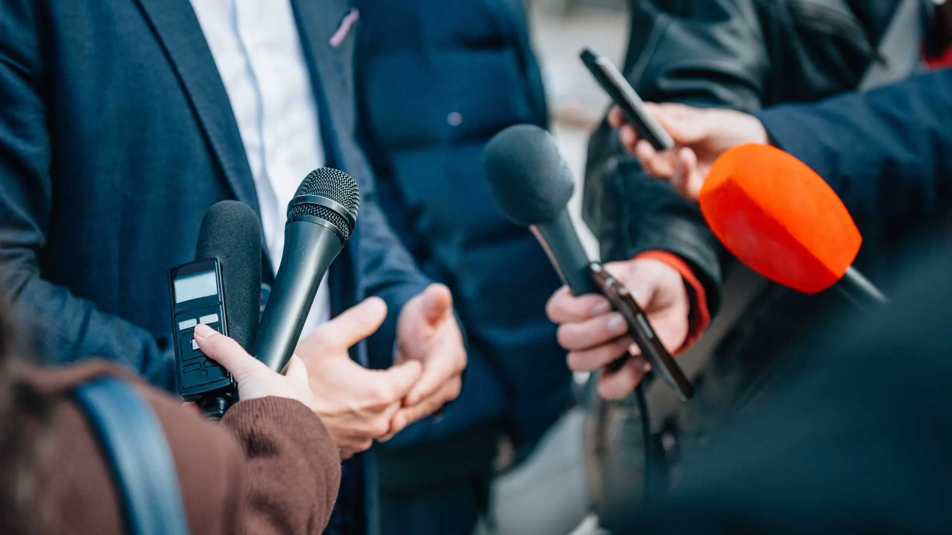 Journalists holding microphones at a media interview
